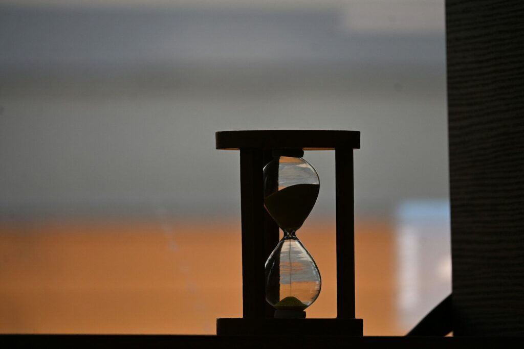 A silhouetted hourglass with sand falling against a blurred background